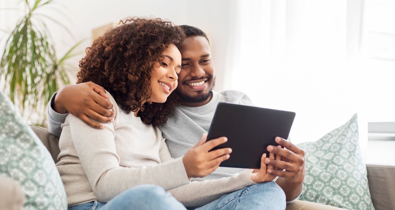 Couple snuggling and smiling while on iPad