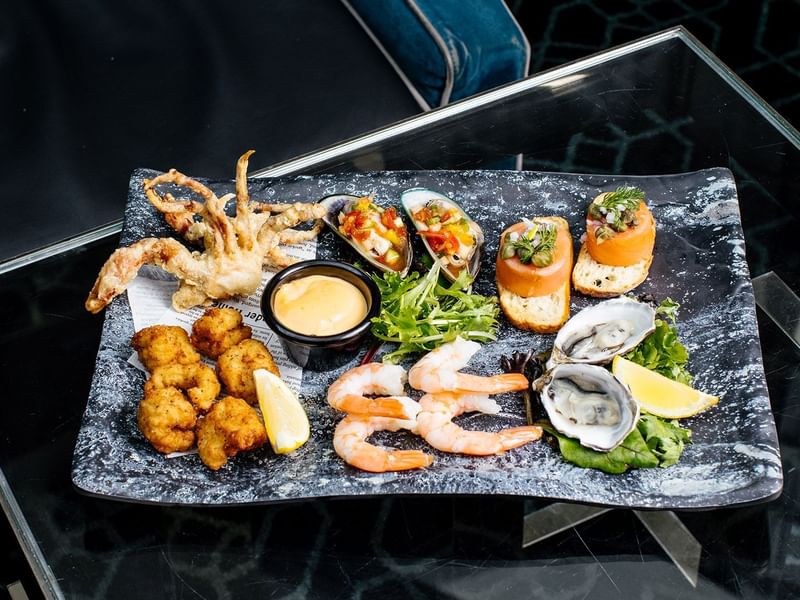 Assorted seafood appetizers on a black slate plate in Lobby Lounge at Crown Metropol Perth