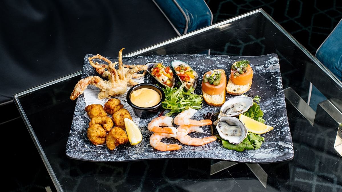 Assorted seafood appetizers on a black slate plate in Lobby Lounge at Crown Metropol Perth