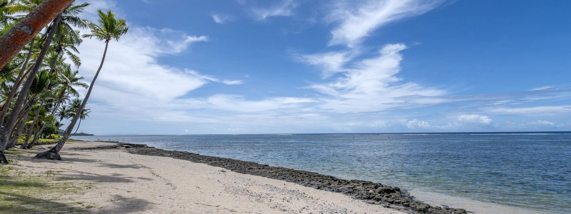 Sandy beach and ocean view with palm trees at Tambua Sands Beach Resort in Sigatoka