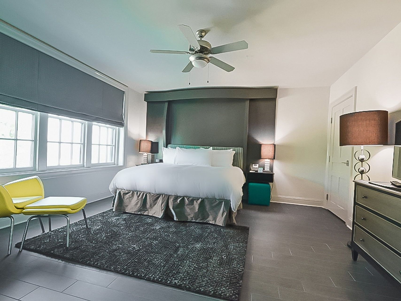 King Bed Gulf View room at The White House Hotel with a plush bed with a grey headboard and a yellow chair by the window