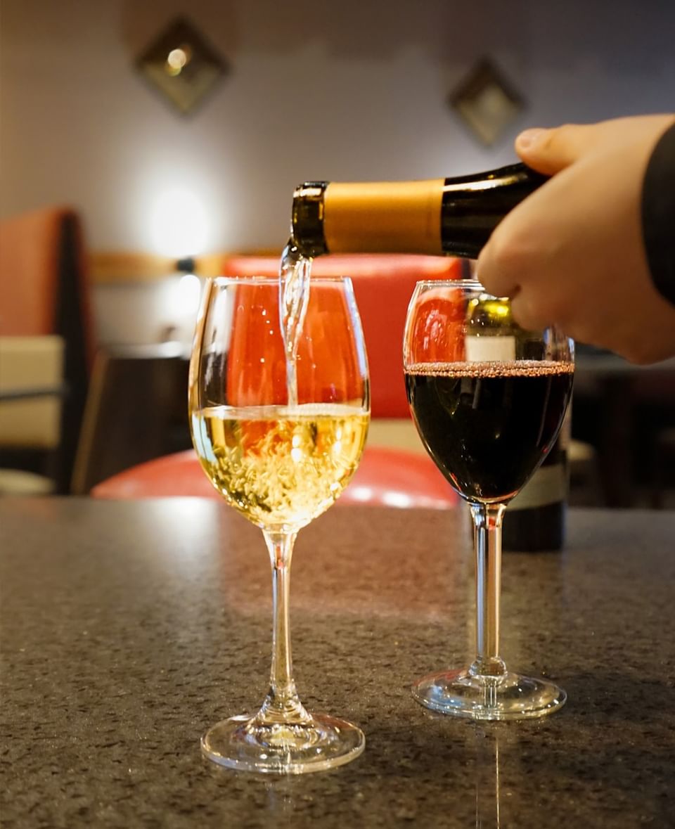 Server pouring white wine into a glass during a fine dining experience in Doe’s Eat Place at Margaritaville Resort Biloxi