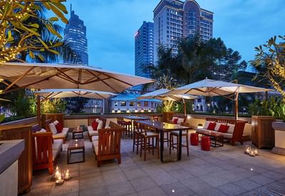 Elegant terrace with palm trees, cozy seating, and ambient lighting at Park Hyatt Saigon