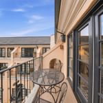 Private balcony with metal bistro table and chairs overlooking courtyard with peach-colored building facade at el PRADO Hotel