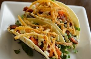 Two soft tacos garnished with crispy fried onion strings on a square plate at Clemson University Conference Center & Inn