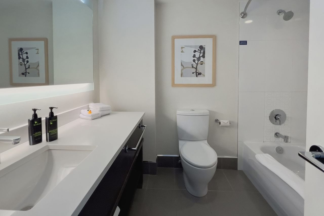 Hotel guestroom washroom with sink, toilet and tub