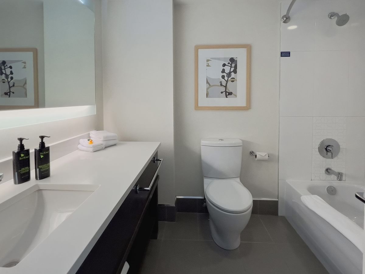 Hotel guestroom washroom with sink, toilet and tub