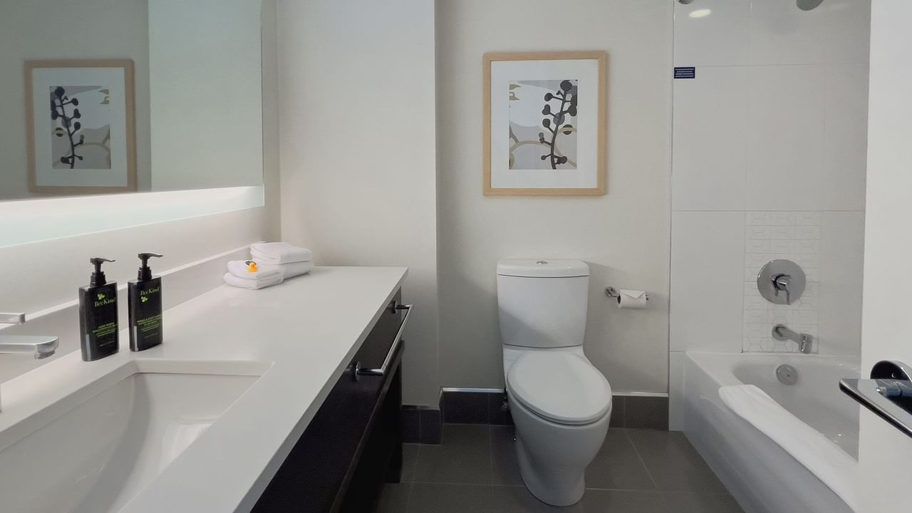 Hotel guestroom washroom with sink, toilet and tub