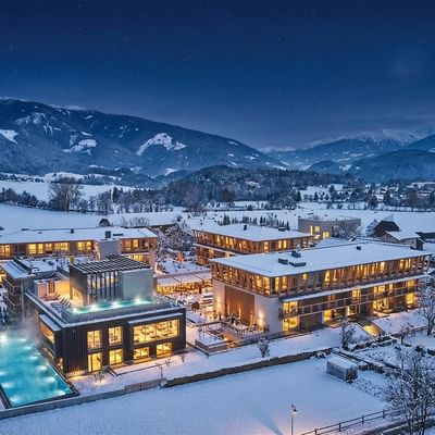 Nachtansicht des beleuchteten Falkensteiner Hotel Kronplatz umgeben von schneebedeckten Bergen