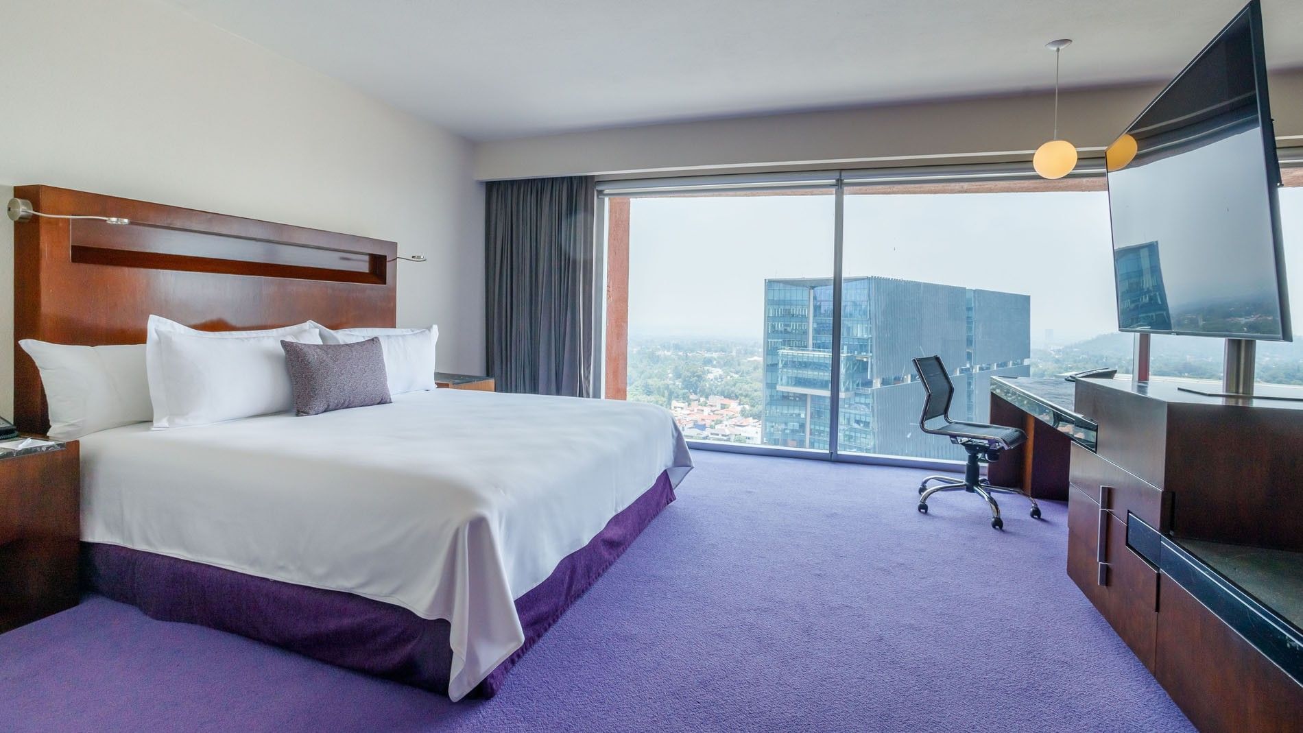 King Master Suite at Camino Real Pedregal Mexico, featuring a large window with a view of a city skyscraper