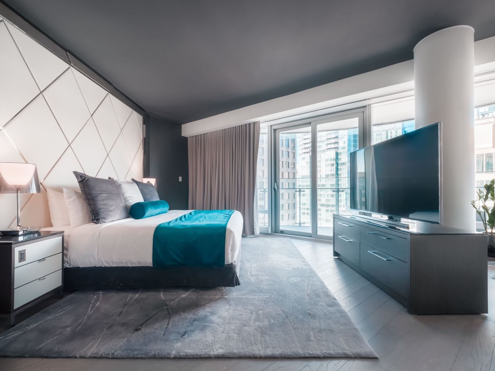 Bed & a large TV in a Signature King room at Paradox Hotels
