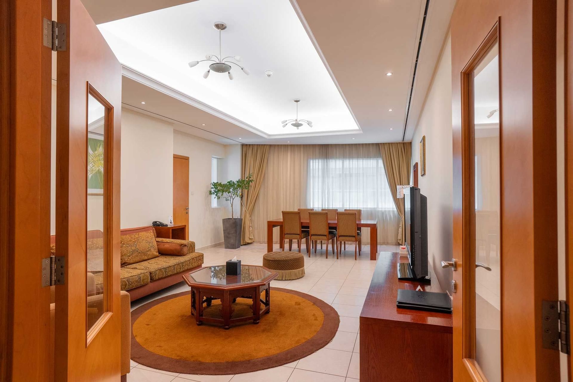 TV lounge with dining table by the window and tiled floors at Tamani Marina Hotel