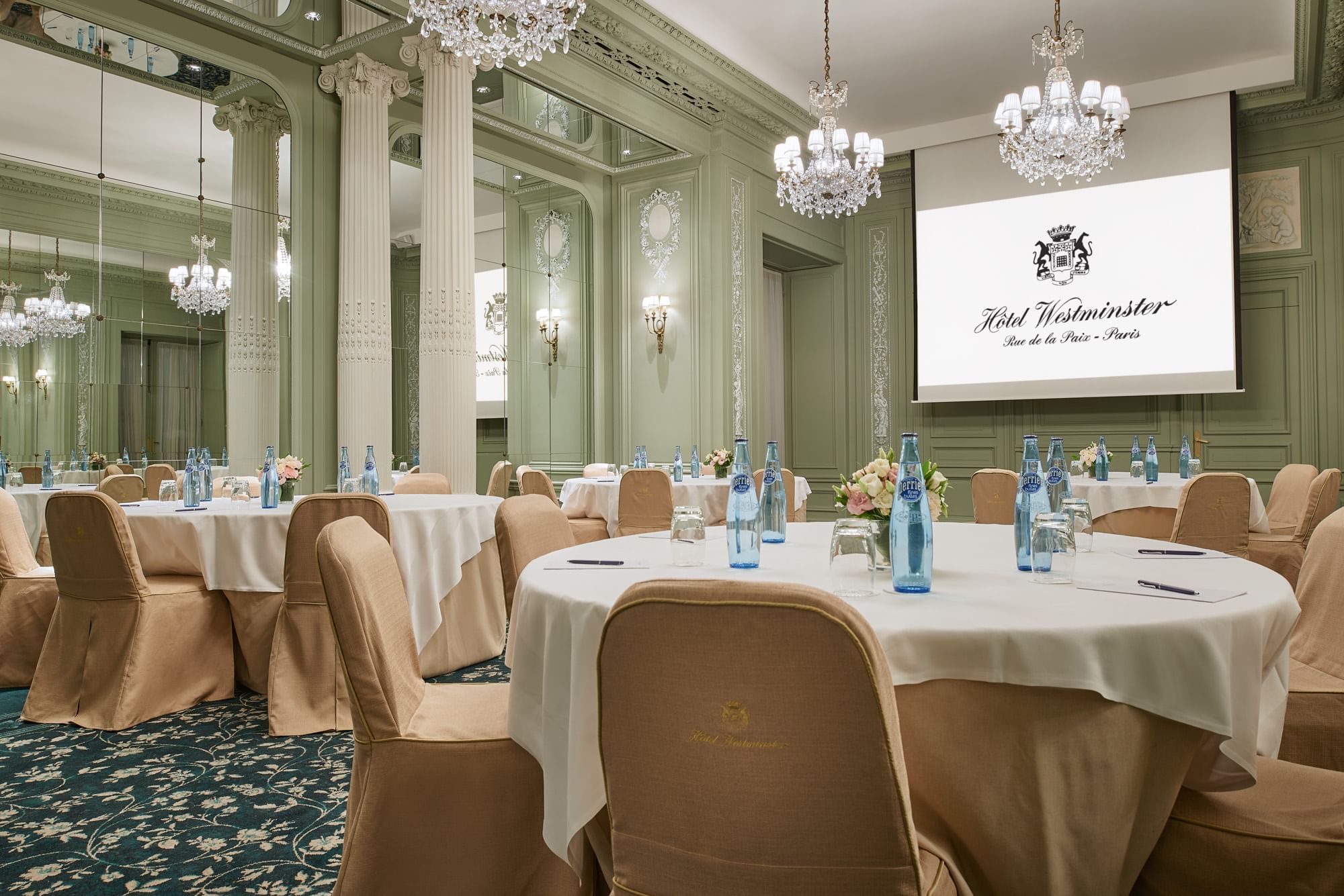 Interior of Récamier meeting room with banquet table set up, projector screen and chandelier at Hôtel Westminster - Paris