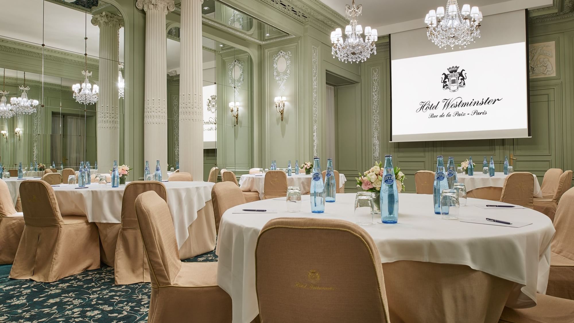 Interior of Récamier meeting room with banquet table set up, projector screen and chandelier at Hôtel Westminster - Paris