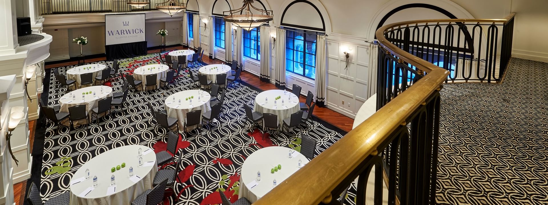 Overhead view of round dining tables, placed by a balcony railing in Buckingham Ballroom at Warwick Allerton Chicago