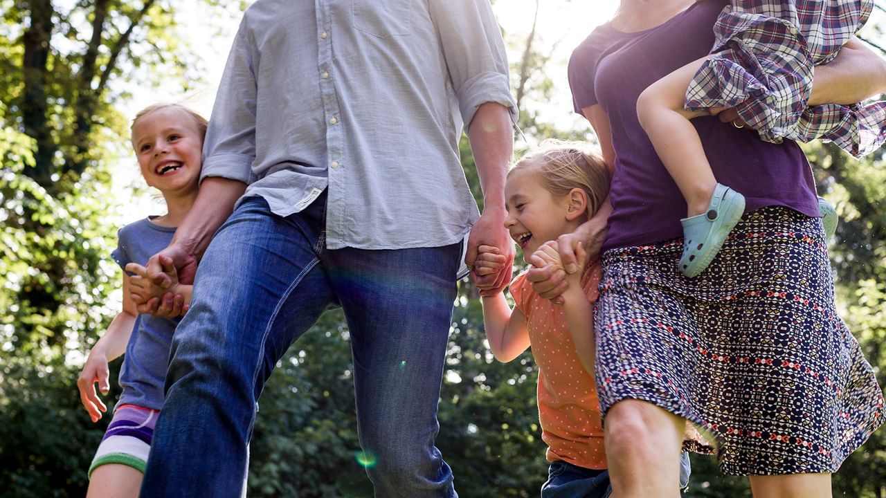 parents walking holding three young children