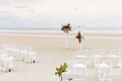 Beach wedding venue with an arch and chairs at The Plaza Resort