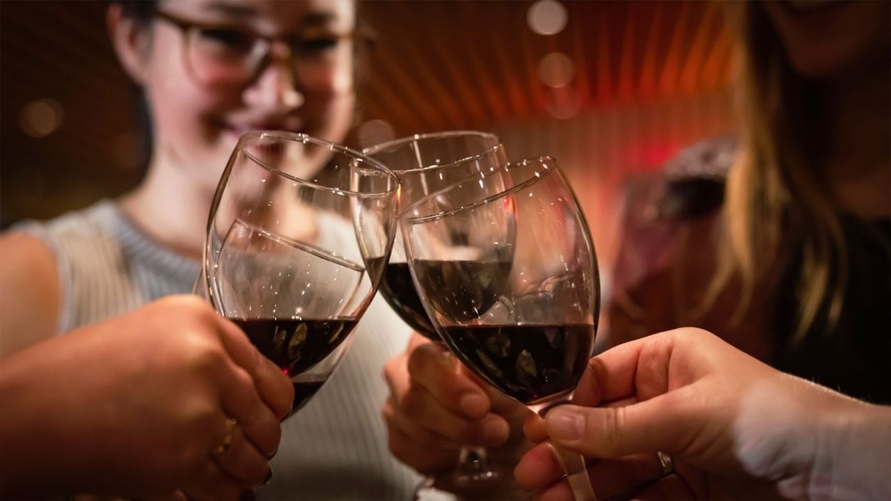 Three people toasting with red wine glasses celebrating fall traditions in Whistler