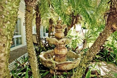 Marble water fountain surrounded by trees at Ocean Lodge Boca Raton