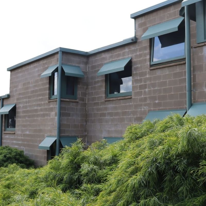 La Trobe University building with green shutters and lush greenery in front.