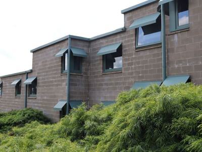 La Trobe University building with green shutters and lush greenery in front.