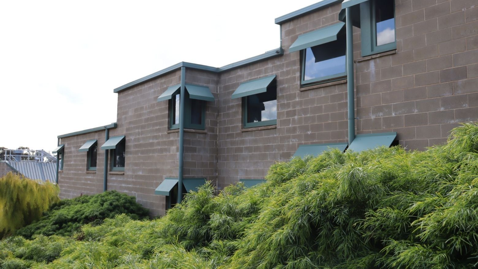 La Trobe University building with green shutters and lush greenery in front.