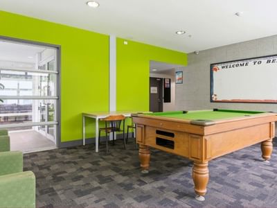 Green pool table and chairs in a lounge area at Student Living Auckland Anzac.