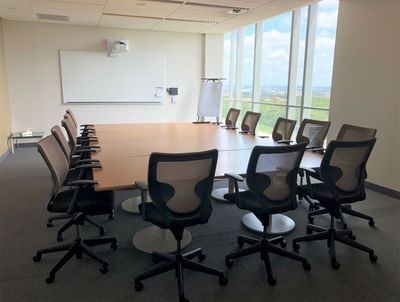 Boardroom setup facing projector screen by the window in meeting room at the Schulich School of Business.