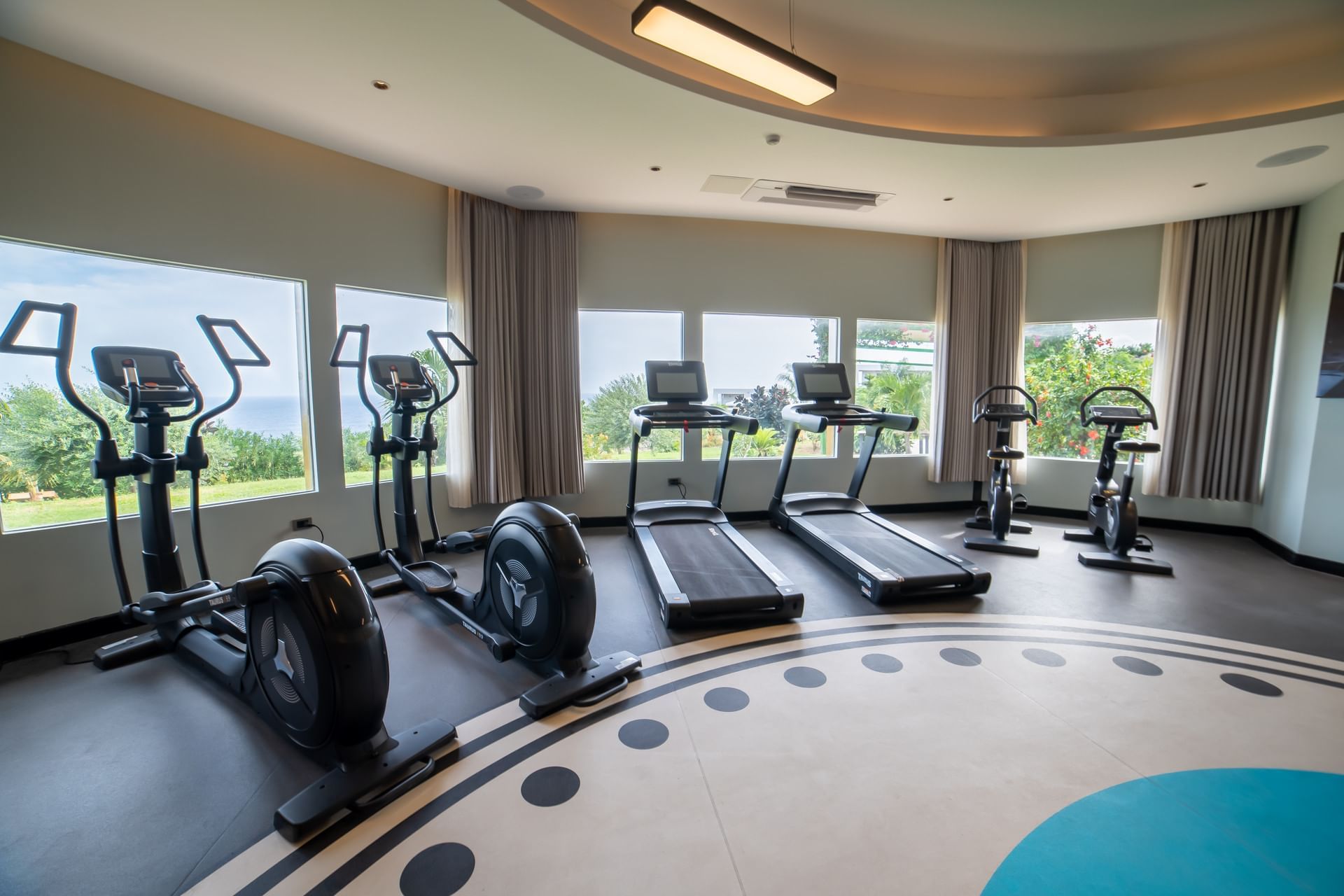 Gym featuring elliptical machines and treadmills with large windows overlooking green landscapes at Golden Rock Resort