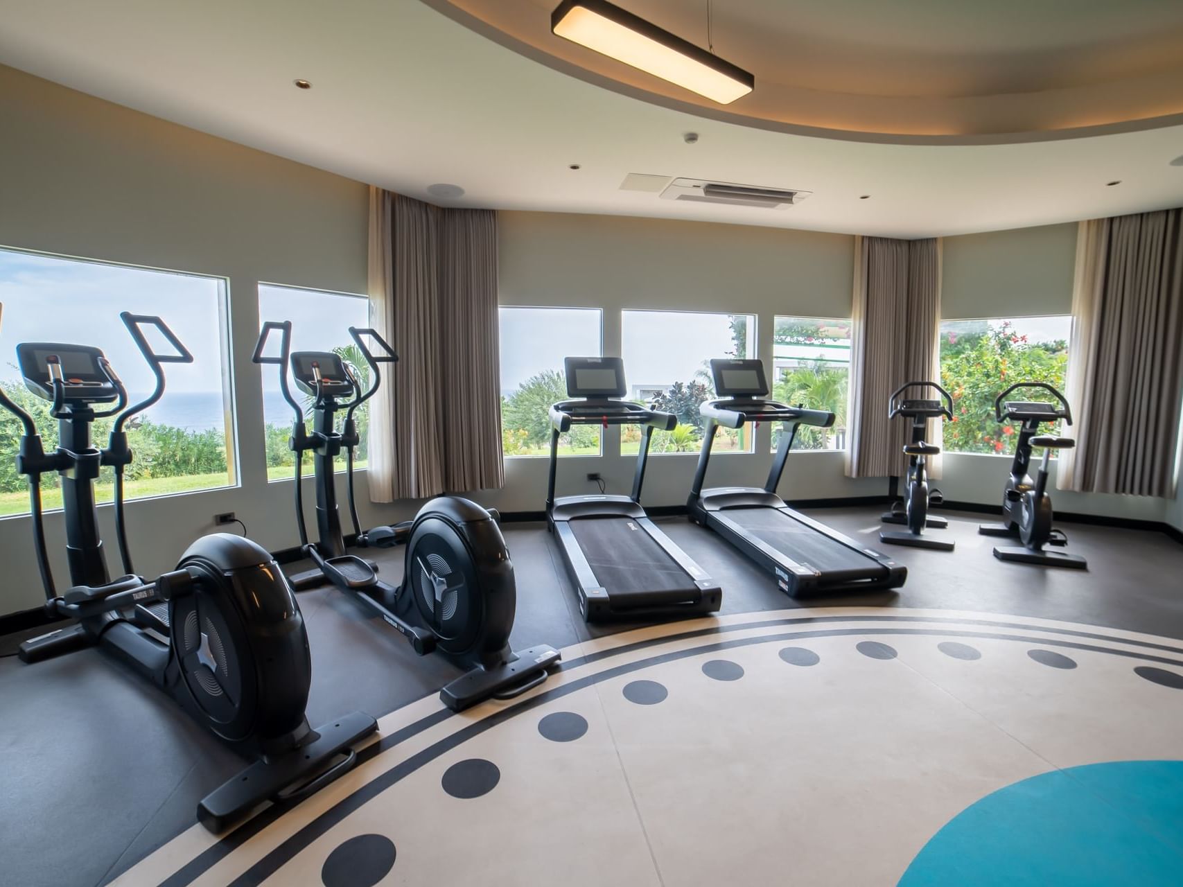 Gym featuring elliptical machines and treadmills with large windows overlooking green landscapes at Golden Rock Resort