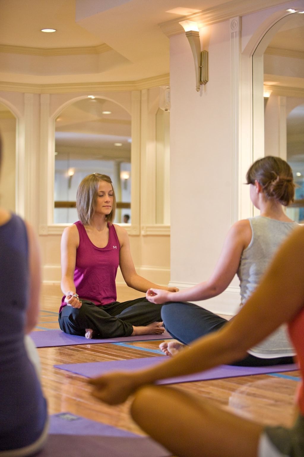 Woman meditating on yoga mat facing instructor during indoor class at Mountain View Grand Resort & Spa