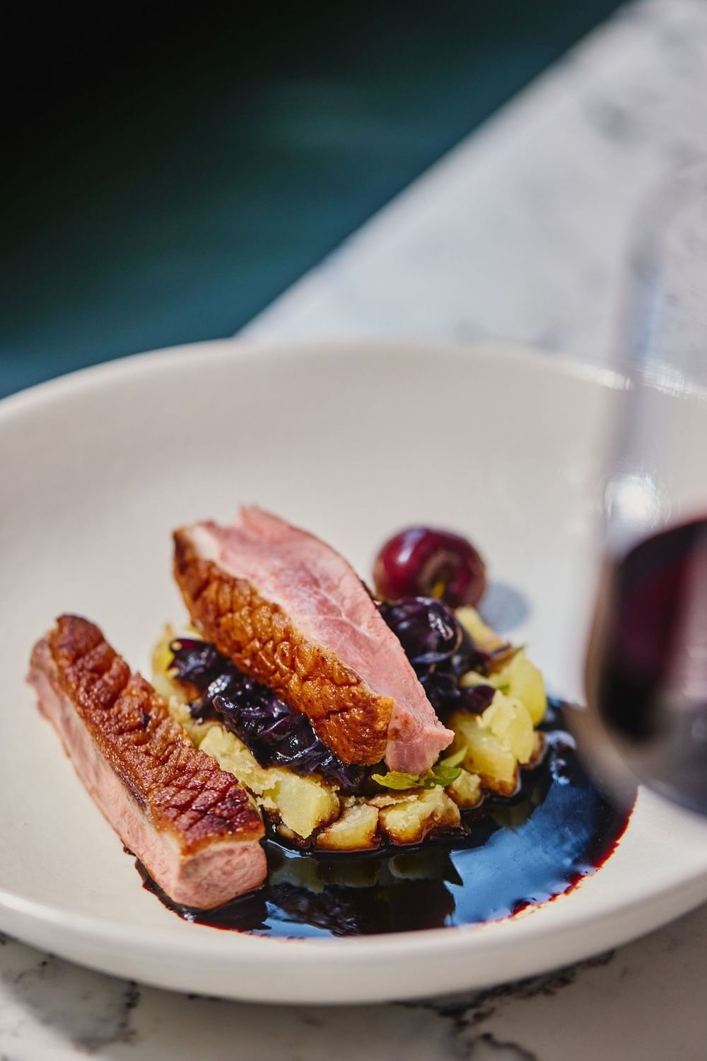 Sliced duck breast with potatoes and cherry sauce on a white plate at The Bedford Hotel Belfast