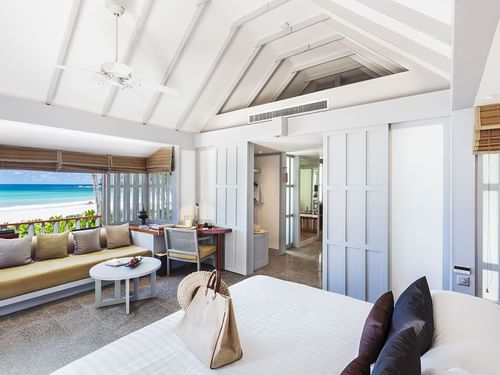 Bright, airy room at The Surin Phuket with a cozy sitting area, modern decor, and sliding doors opening to the beach