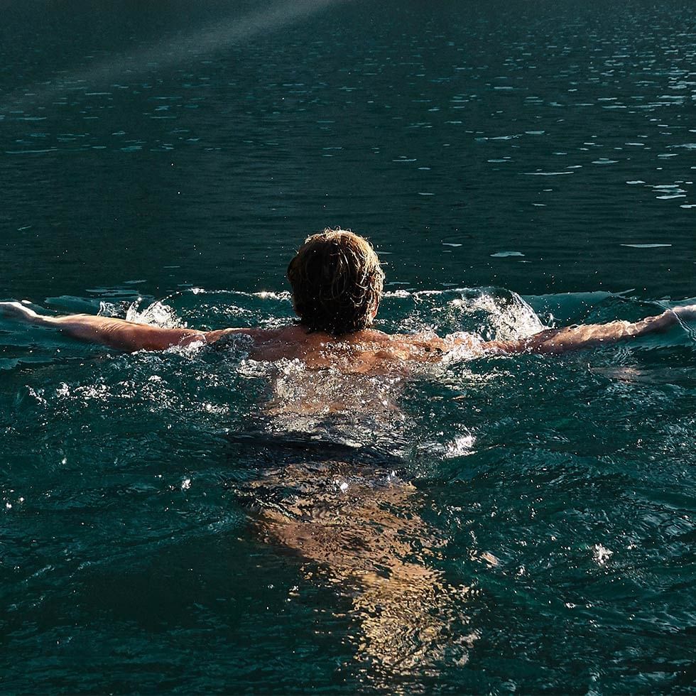 A man swimming in the water near Falkensteiner Hotels