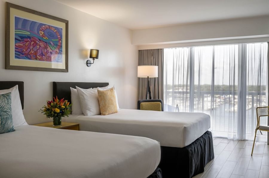 Twin beds by a yellow nightstand under colorful framed art in Water View at Warwick Paradise Island Bahamas