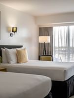 Twin beds by a yellow nightstand under colorful framed art in Water View at Warwick Paradise Island Bahamas