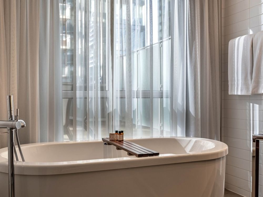 Élégante salle de bains avec baignoire et articles de toilette au Warwick Le Crystal – Montréal.