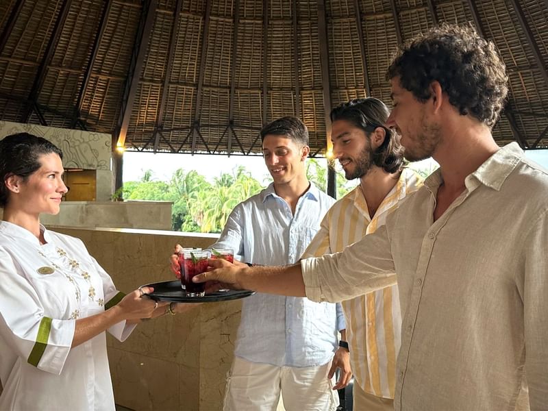 The server holding a tray of drinks with three men receiving them at Fiesta Americana