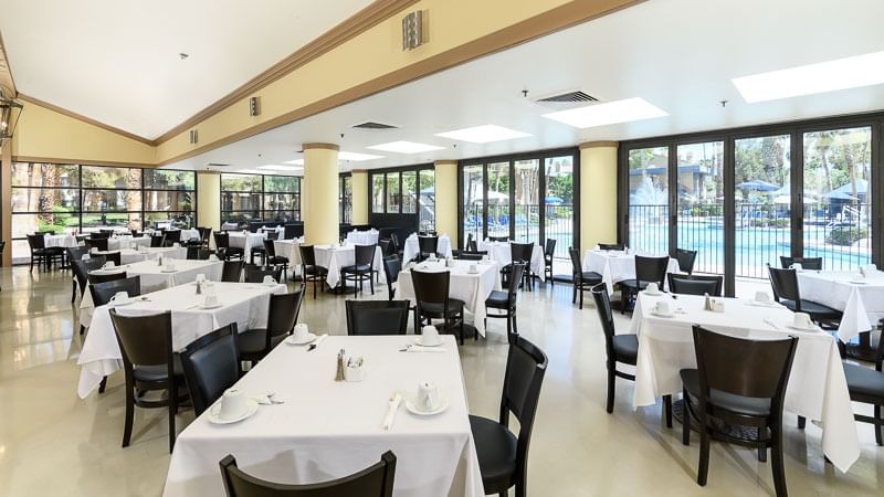 A large dining room with white tablecloths and black chairs
