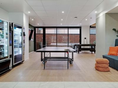 Modern recreation room with ping pong tables, vending machines, and lounge seating at UniLodge Auckland Central.