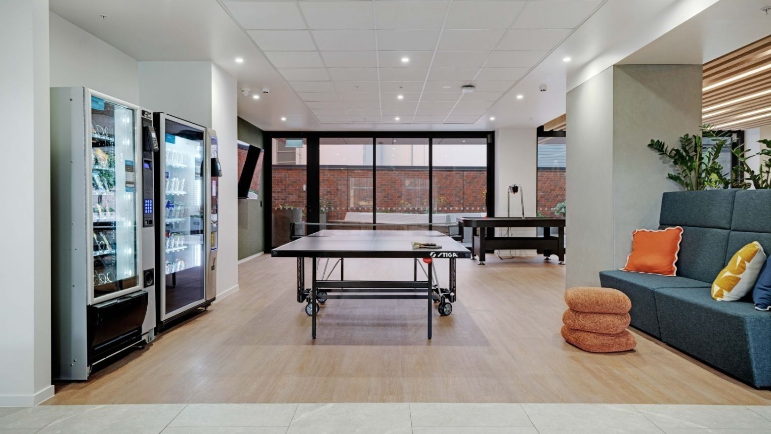 Modern recreation room with ping pong tables, vending machines, and lounge seating at UniLodge Auckland Central.