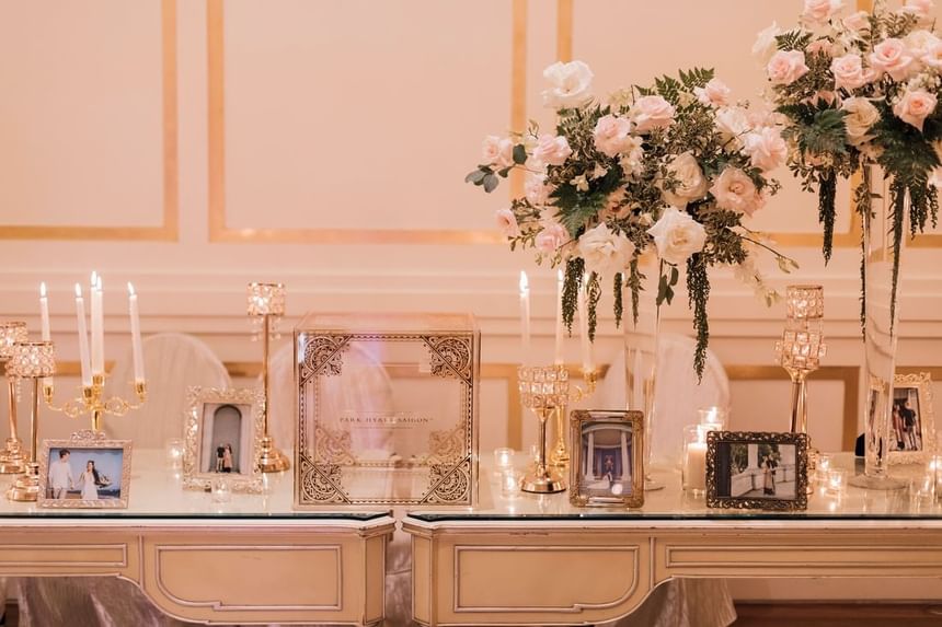 Elegant display with floral arrangements, candles, and framed pictures on a glass table for an event at Park Hyatt Saigon