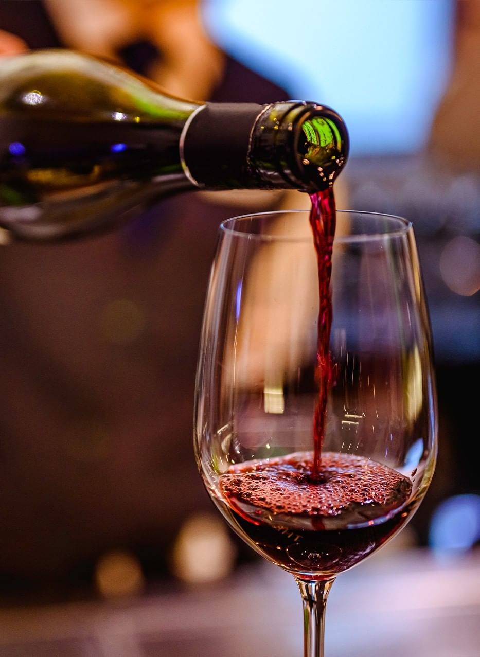 Close-up of deep red wine being poured from a bottle into a glass at Gott's Bar & Kitchen, The Met Hotel Leeds, England