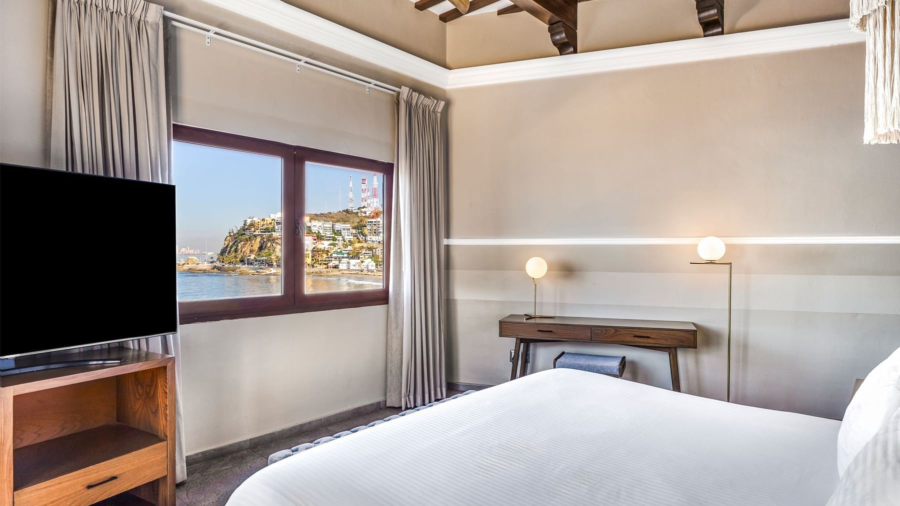 Spacious room featuring a large bed, TV, and a window with an ocean view at Curamoria Collection