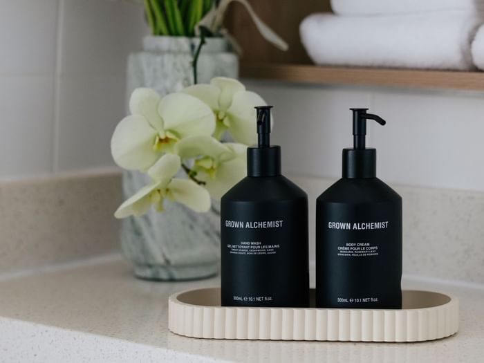 Sunset View Twin at Elysium Manly with Grown Alchemist bottles on a ribbed tray by a glass vase under folded bath towels