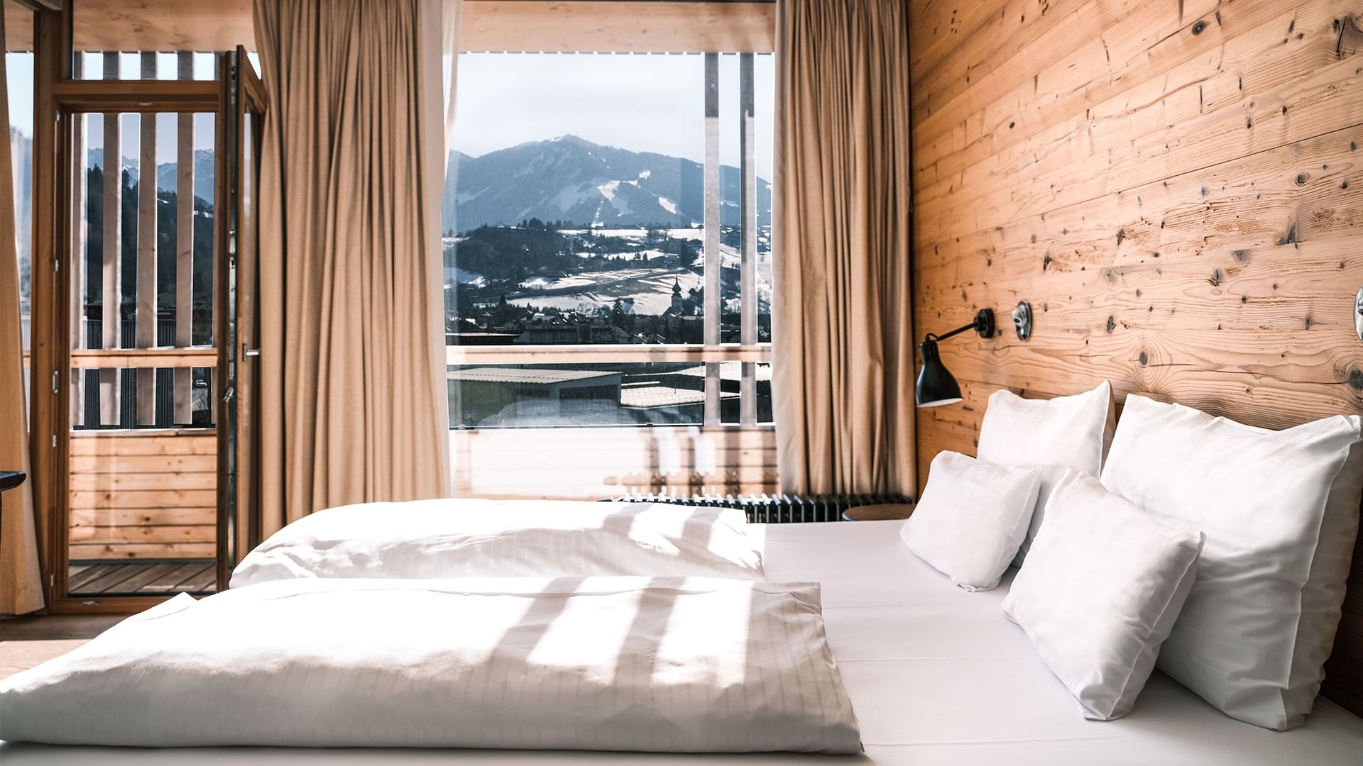 A cozy bedroom with a wooden wall and mountain view at Falkensteiner Hotel Schladming