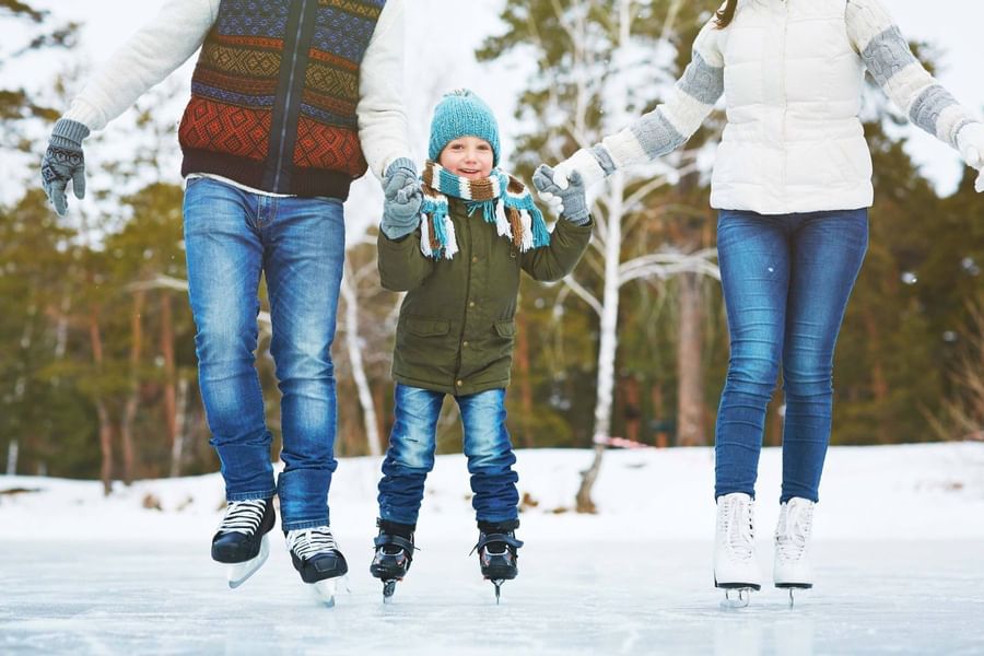 child holding hands with parents and iceskating