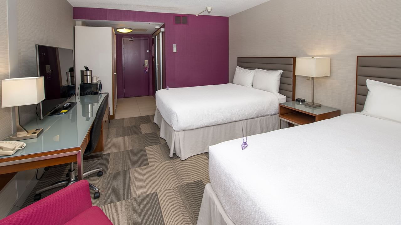 Two beds, TV, lamp, and chair in a hotel room.