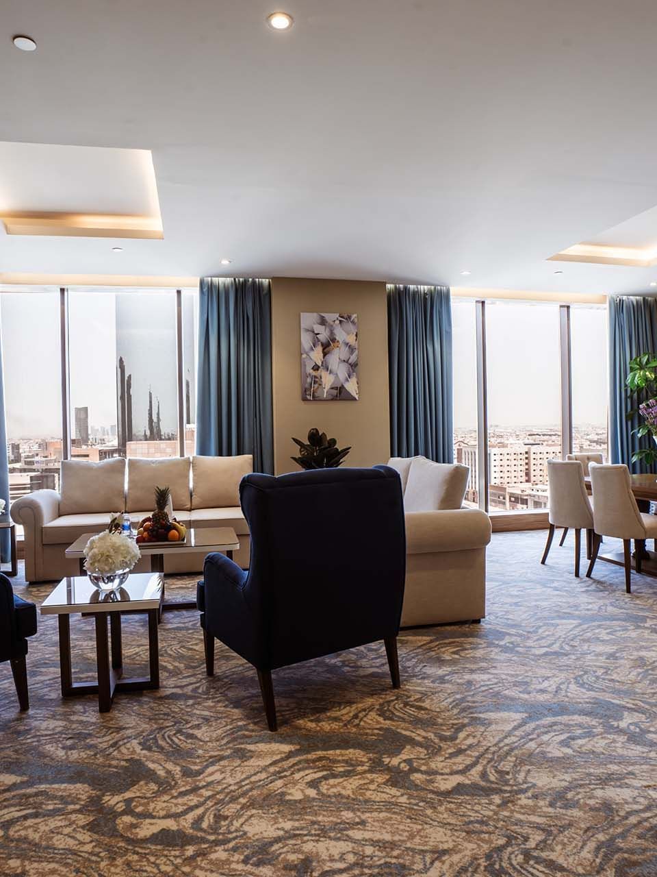 Living room with blue wingback chairs and a dining set in Royal Suite at Cantonal Hotel by Warwick Riyadh