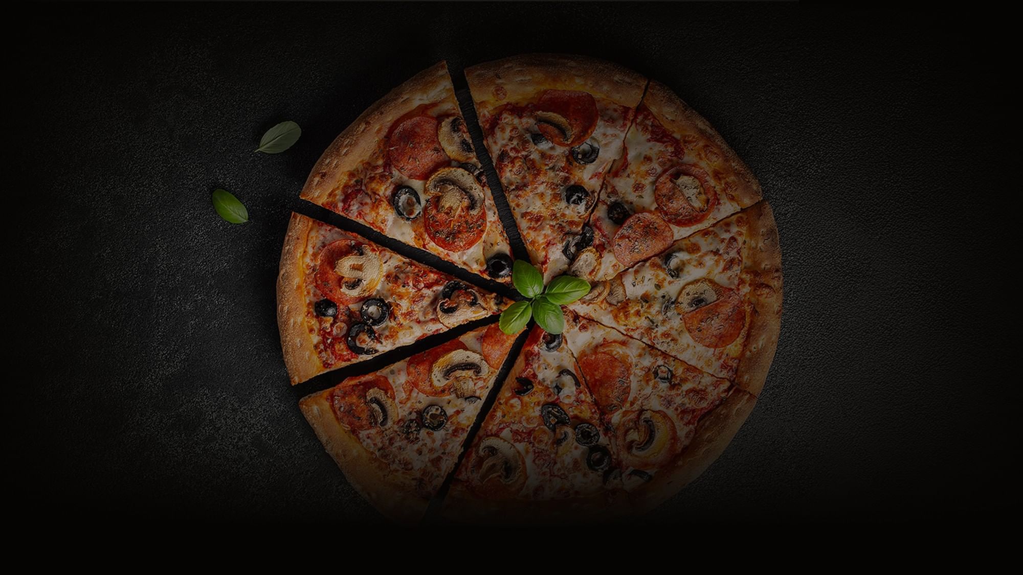 Top view of a sliced pepperoni pizza with mushrooms on a black background at  Camino Real Pedregal Mexico